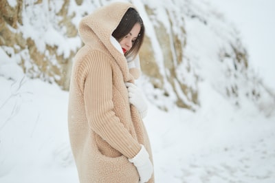 女人棕色小熊连帽外套站在布朗博尔德在白天雪覆盖
